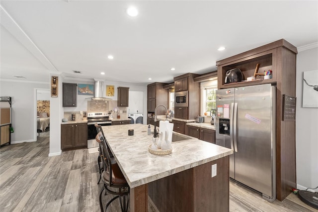 kitchen featuring crown molding, stainless steel appliances, a sink, and wall chimney exhaust hood