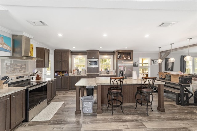 kitchen featuring crown molding, dark brown cabinetry, appliances with stainless steel finishes, ventilation hood, and visible vents