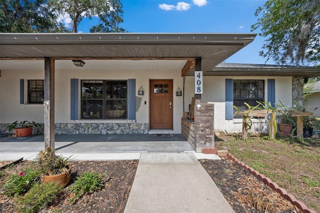 408 Etheredge St, Bushnell, FL 33513 - doorway to property with a porch, stucco siding, and stone siding