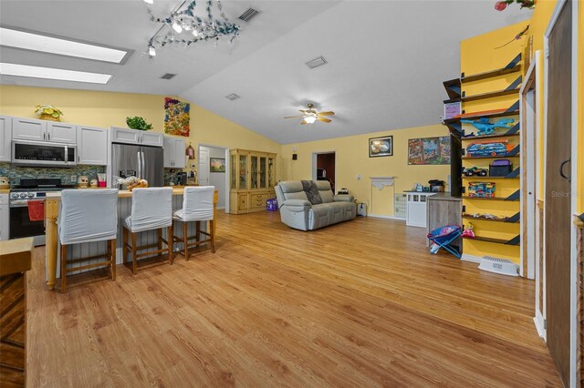 408 Etheredge St, Bushnell, FL 33513 - living room featuring vaulted ceiling, light wood-style floors, ceiling fan, and a skylight