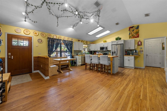 408 Etheredge St, Bushnell, FL 33513 - kitchen featuring appliances with stainless steel finishes, rail lighting, a kitchen bar, light countertops, and lofted ceiling