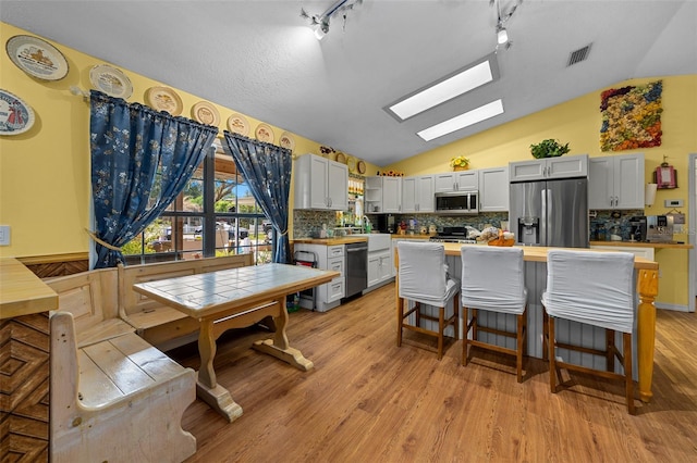 408 Etheredge St, Bushnell, FL 33513 - kitchen featuring appliances with stainless steel finishes, lofted ceiling, decorative backsplash, light wood-style flooring, and a skylight