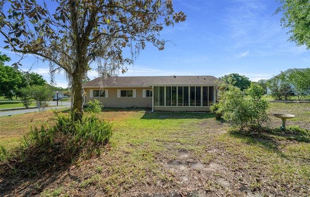 back of property with a sunroom and a yard