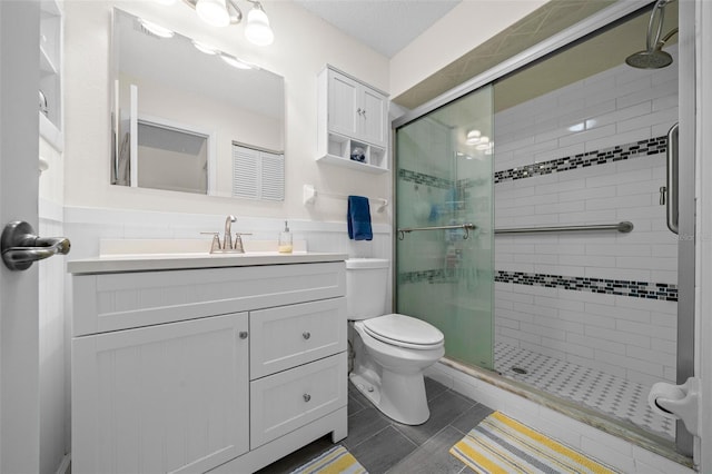 bathroom with a shower stall, toilet, and vanity
