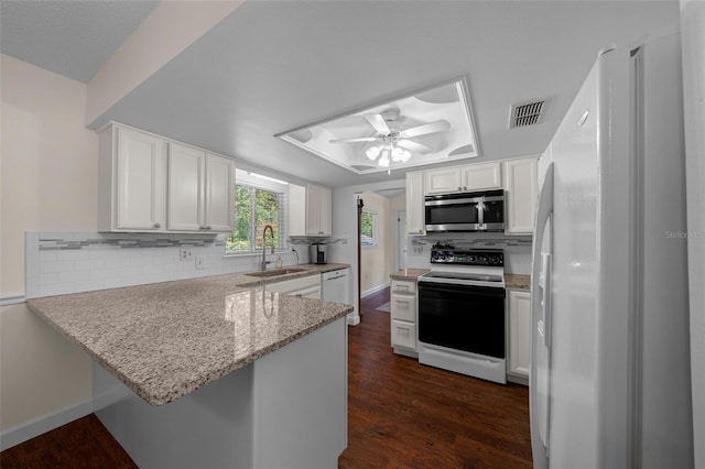 kitchen featuring white appliances, a sink, a raised ceiling, a peninsula, and a ceiling fan