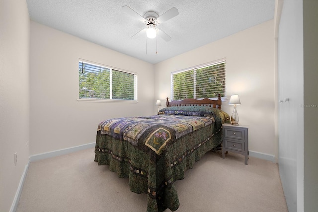 bedroom with light carpet, baseboards, a textured ceiling, and ceiling fan