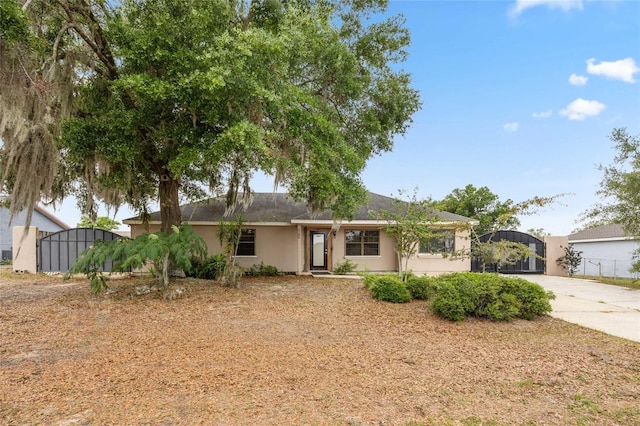 single story home featuring a gate, stucco siding, fence, and concrete driveway