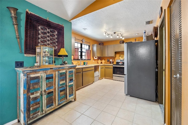 kitchen with appliances with stainless steel finishes, a textured ceiling, light countertops, light tile patterned floors, and a sink