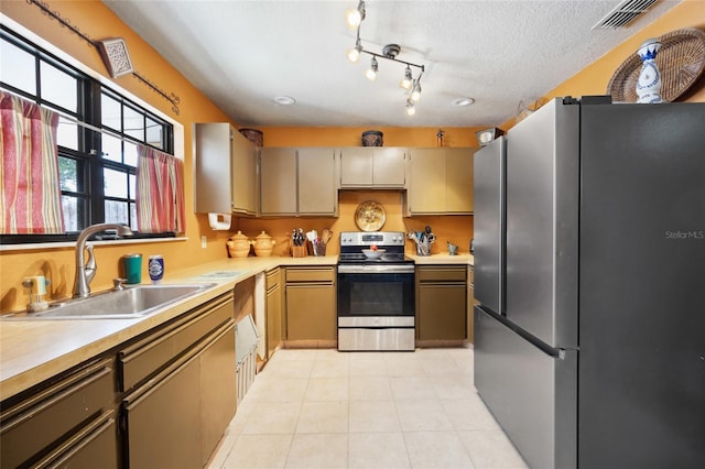 kitchen featuring stainless steel appliances, a sink, light countertops, a textured ceiling, and light tile patterned flooring