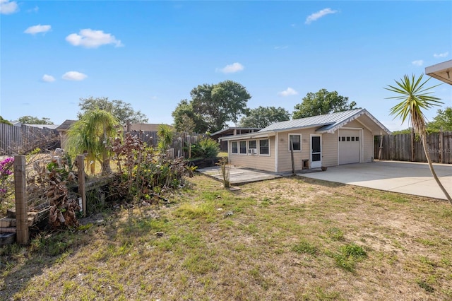 back of property featuring driveway, a patio, metal roof, and a garage
