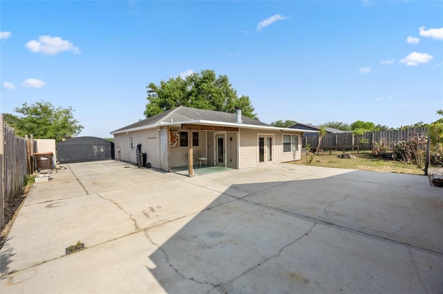 rear view of house featuring french doors, a fenced backyard, driveway, and a patio