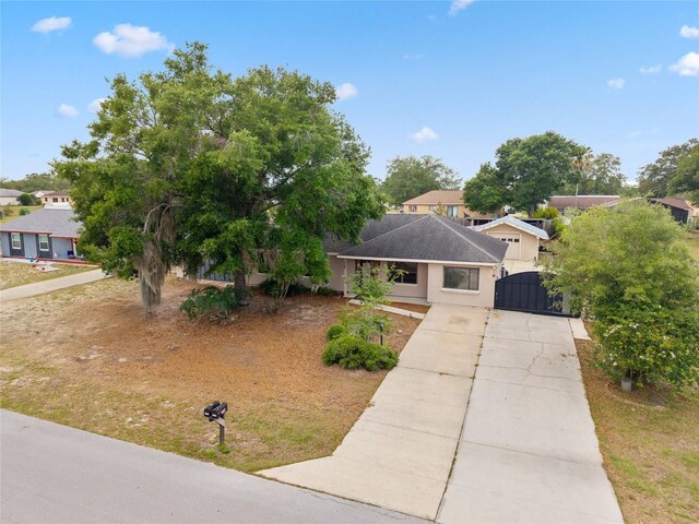 view of front facade featuring concrete driveway, a gate, stucco siding, and a residential view