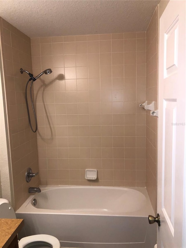 bathroom with washtub / shower combination, vanity, toilet, and a textured ceiling