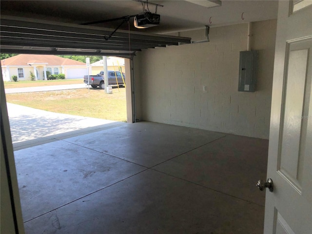 garage featuring a garage door opener, electric panel, and concrete block wall