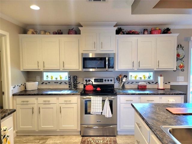 7030 SE 120th Ct, Morriston, FL 32668 - kitchen featuring crown molding, white cabinets, appliances with stainless steel finishes, dark stone counters, and visible vents