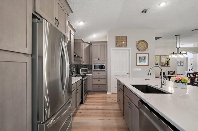 8545 SE 168th Kittredge Loop, The Villages, FL 32162 - kitchen with appliances with stainless steel finishes, a textured ceiling, light wood-style floors, hanging light fixtures, and a chandelier