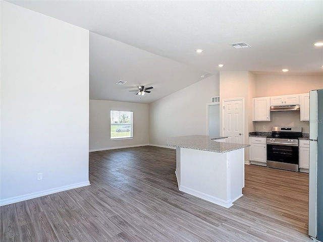 kitchen with stainless steel range with electric stovetop, wood finished floors, lofted ceiling, under cabinet range hood, and visible vents