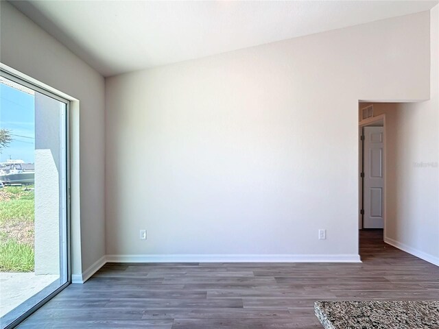 empty room with baseboards, visible vents, a wealth of natural light, and wood finished floors