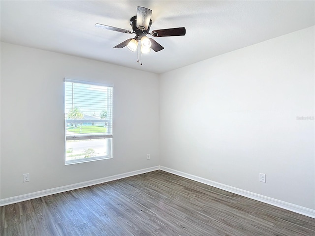 spare room featuring baseboards, ceiling fan, and dark wood-type flooring