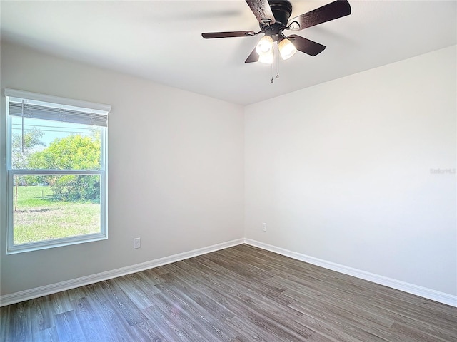 spare room featuring baseboards, a ceiling fan, and dark wood-style flooring