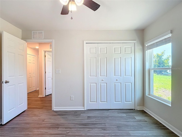 unfurnished bedroom with visible vents, baseboards, and dark wood-type flooring