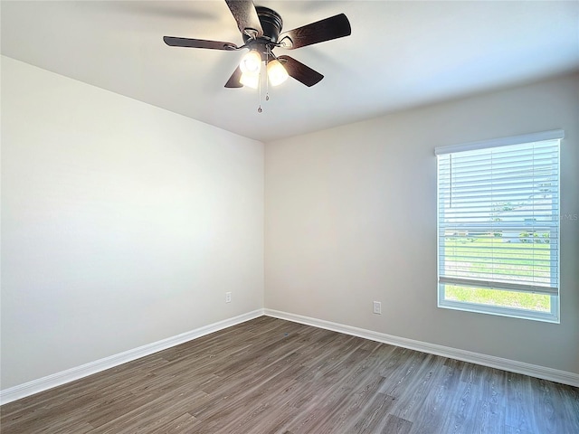 spare room with a healthy amount of sunlight, baseboards, and dark wood-type flooring