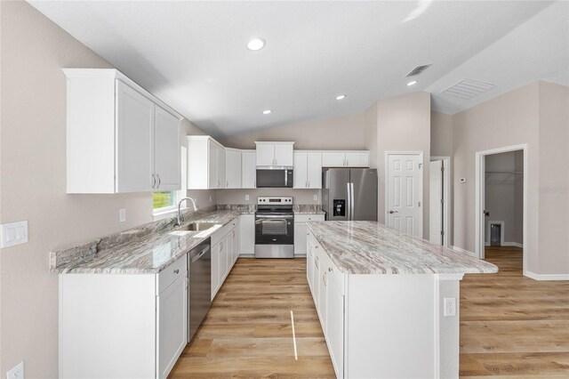 kitchen featuring a sink, appliances with stainless steel finishes, light wood-style floors, and a kitchen island