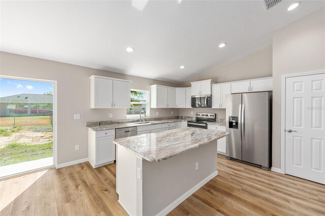 kitchen with a kitchen island, light wood-type flooring, white cabinets, a sink, and stainless steel appliances