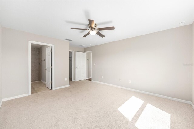 unfurnished bedroom featuring visible vents, light carpet, baseboards, ceiling fan, and a spacious closet