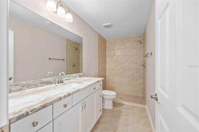 bathroom featuring visible vents, a tile shower, and vanity