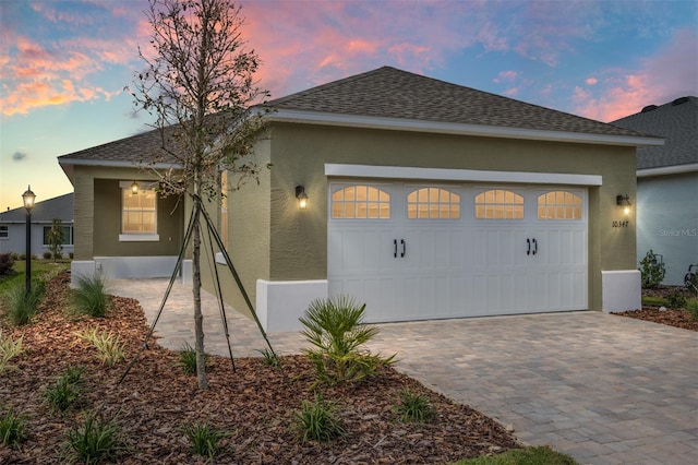 10347 SW 99th Ln, Ocala, FL 34481 - property exterior at dusk with stucco siding, an attached garage, roof with shingles, and driveway