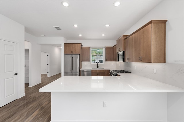 10347 SW 99th Ln, Ocala, FL 34481 - kitchen with stainless steel appliances, a sink, a peninsula, dark wood-type flooring, and backsplash