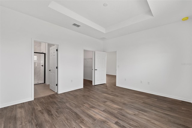 10347 SW 99th Ln, Ocala, FL 34481 - unfurnished bedroom featuring a tray ceiling, wood finished floors, a walk in closet, baseboards, and ensuite bath