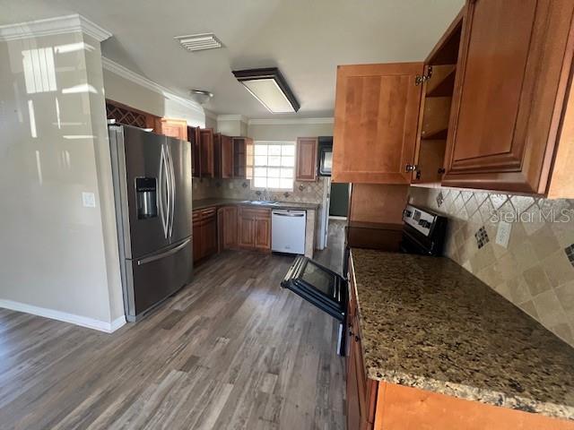kitchen featuring brown cabinets, open shelves, appliances with stainless steel finishes, wood finished floors, and ornamental molding