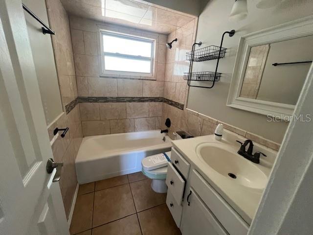 full bathroom with shower / bathtub combination, tile patterned flooring, vanity, and toilet