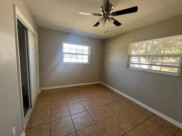 unfurnished bedroom featuring baseboards, tile patterned flooring, a closet, and ceiling fan