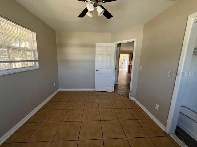 tiled spare room featuring baseboards and ceiling fan
