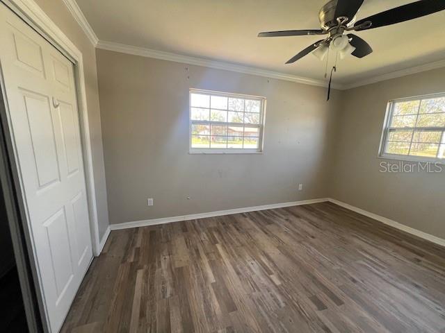 unfurnished bedroom featuring baseboards, multiple windows, and dark wood finished floors