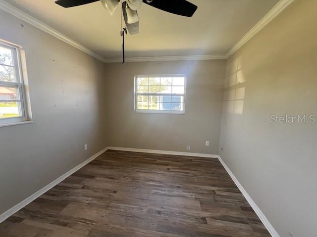 empty room featuring baseboards, a ceiling fan, wood finished floors, and ornamental molding