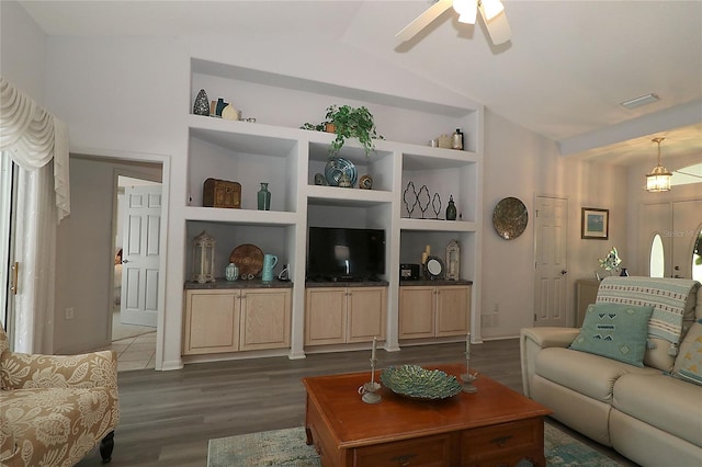 living area featuring a ceiling fan, dark wood-style flooring, visible vents, built in shelves, and lofted ceiling