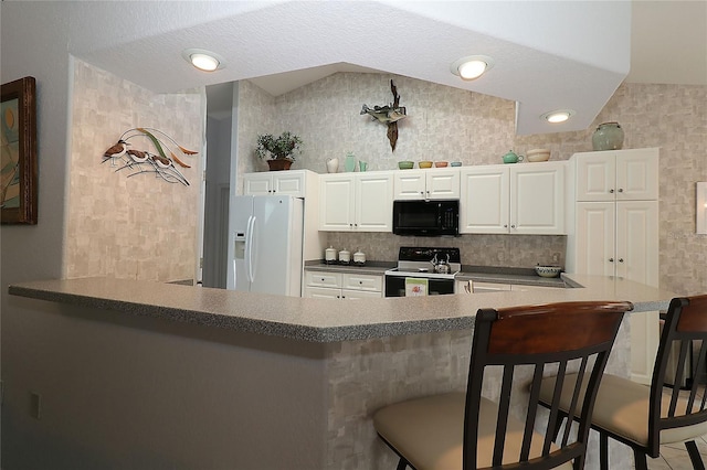 kitchen featuring black microwave, a kitchen breakfast bar, white fridge with ice dispenser, vaulted ceiling, and range with electric stovetop