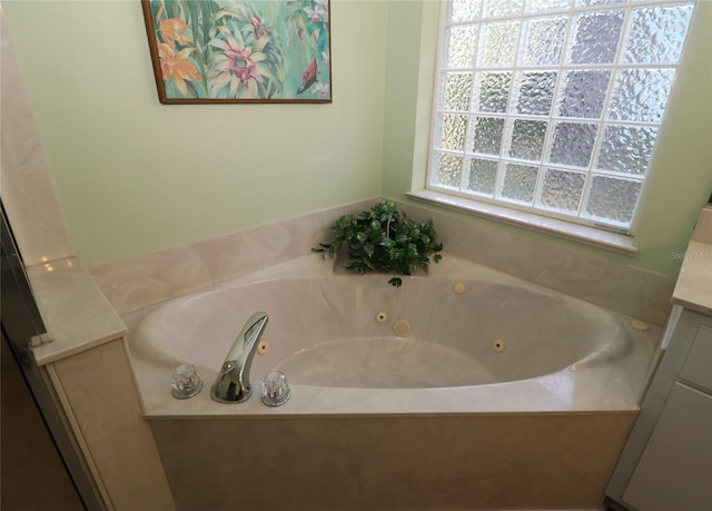 bathroom with a tub with jets and vanity