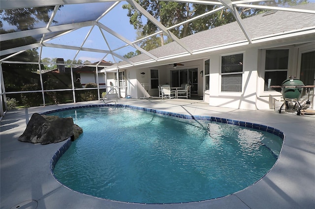 outdoor pool featuring glass enclosure, ceiling fan, and a patio area