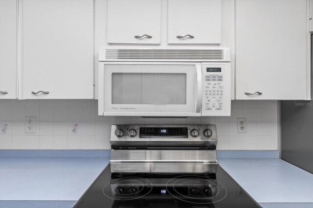 340 E Glassboro Ct Unit 4B, Hernando, FL 34442 - kitchen with white microwave, stainless steel range with electric stovetop, light countertops, white cabinetry, and decorative backsplash