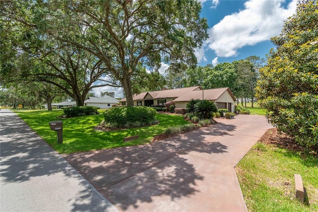 view of home's community with a lawn, an attached garage, and concrete driveway