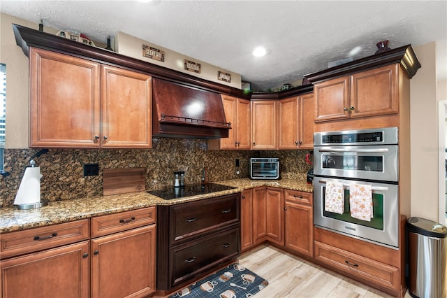 kitchen featuring a textured ceiling, decorative backsplash, premium range hood, and double oven