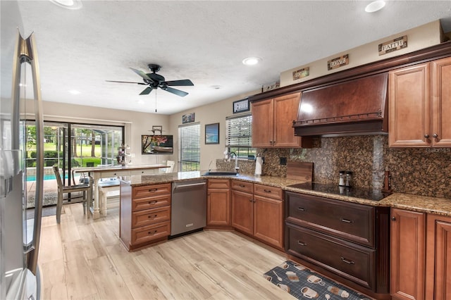 kitchen with ceiling fan, dishwasher, a sink, premium range hood, and a peninsula