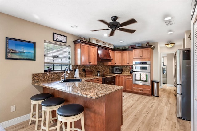 kitchen with ceiling fan, custom range hood, a sink, a peninsula, and stainless steel appliances
