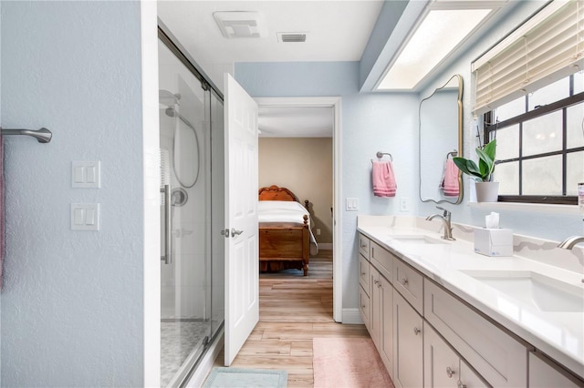 bathroom featuring a stall shower, visible vents, a sink, and wood finished floors