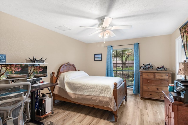 bedroom featuring visible vents, a textured ceiling, light wood-style flooring, and ceiling fan